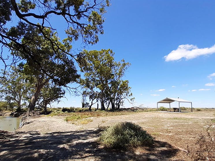 The banks of the Lachlan River at Lachlan River campground with a barbecue shelter in the distance