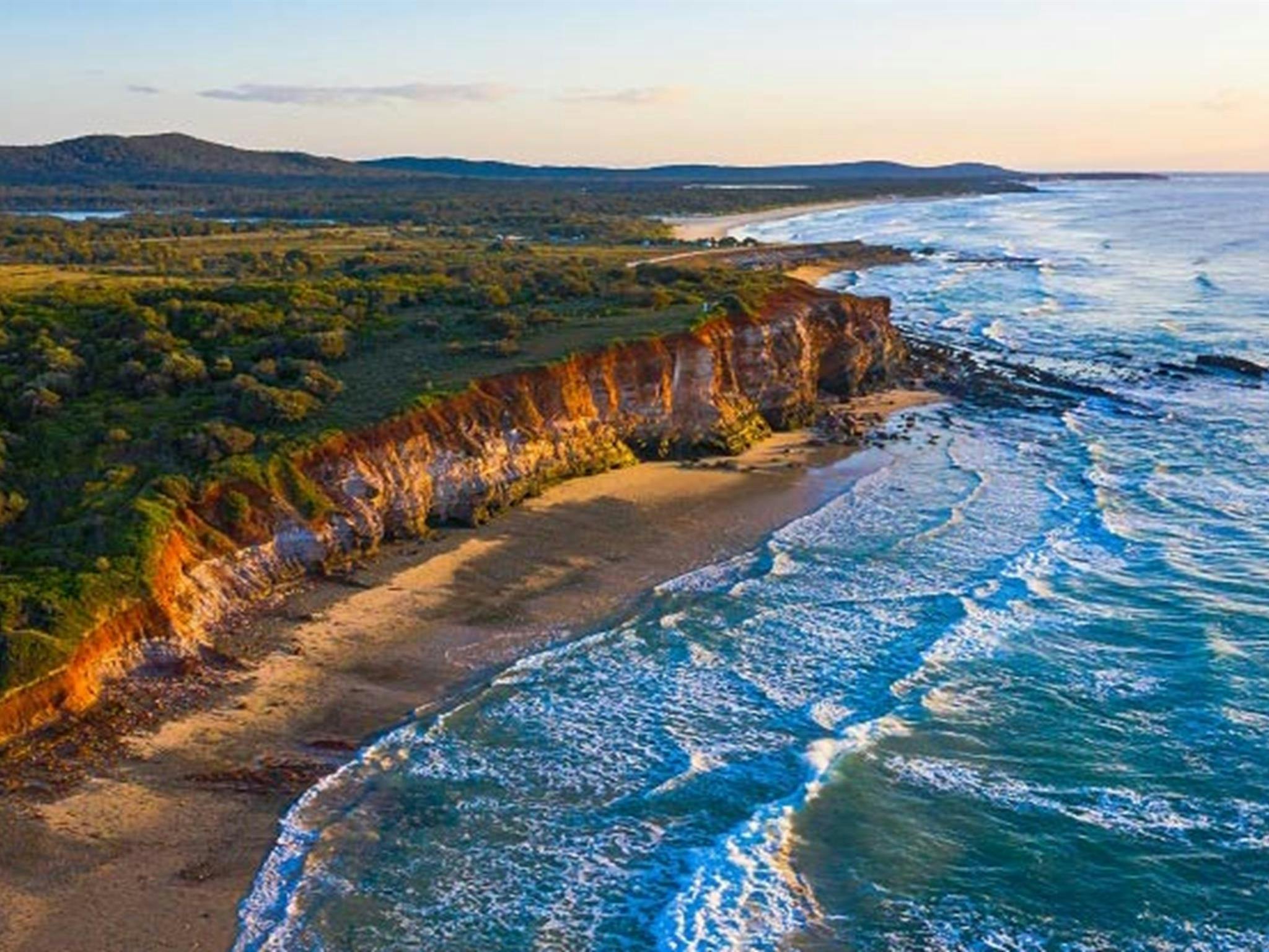 Luftaufnahme der roten Klippen und des Ozeans am Campingplatz Red Cliff im Yuraygir-Nationalpark. Foto: