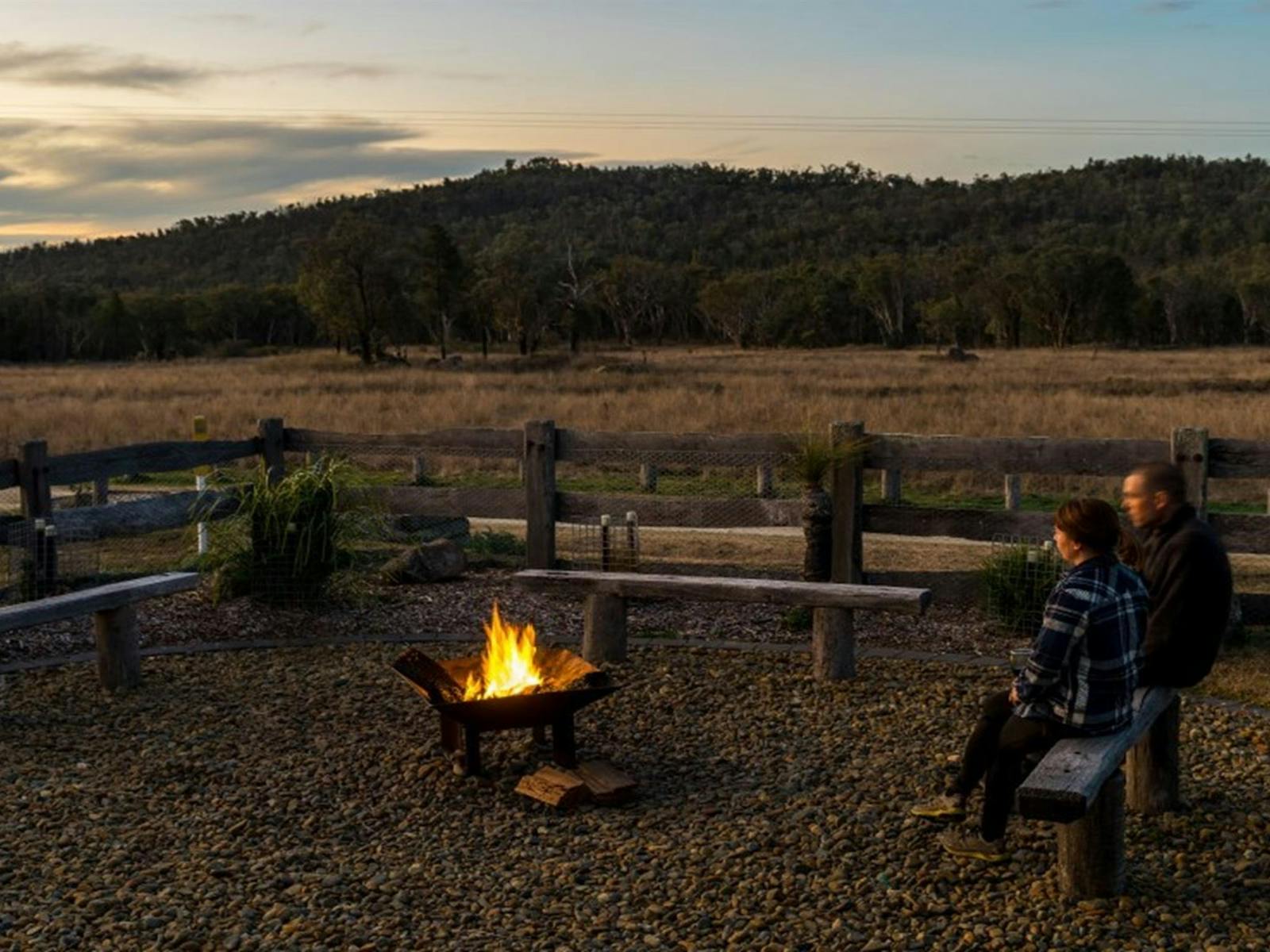 2 people sitting on a bench by the firepit at Lavender Vale Homestead. Photo © DPE