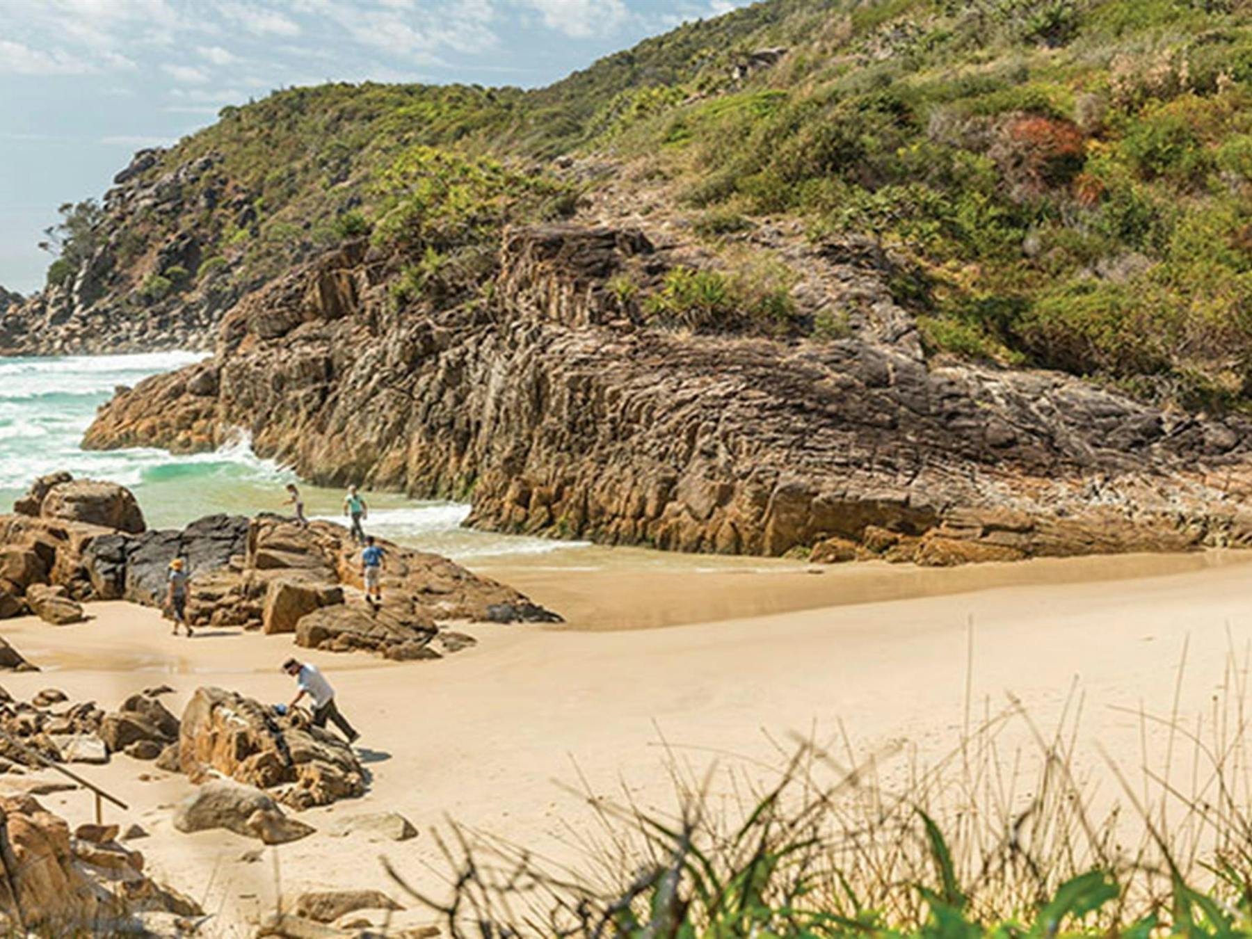 A family exploring the rocks at Little Bay beach in Arakoon National Park. Photo: David