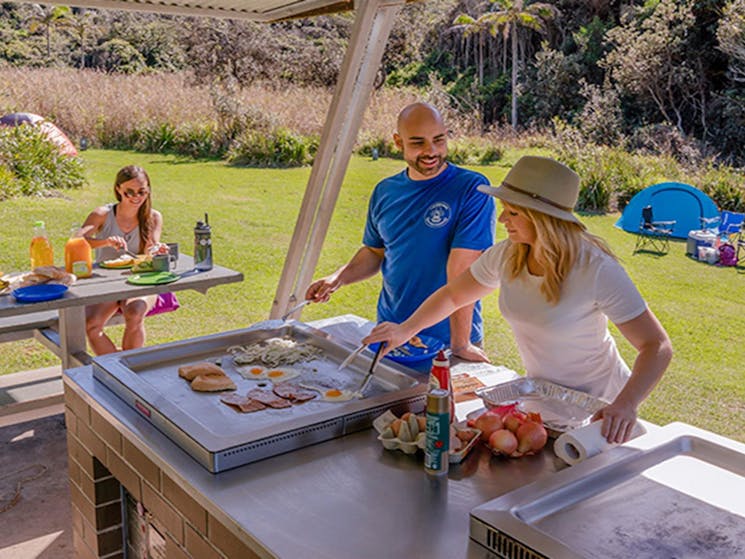 Campers under the barbecue shelter cooking and enjoying breakfast, Bouddi National Park. Photo: John
