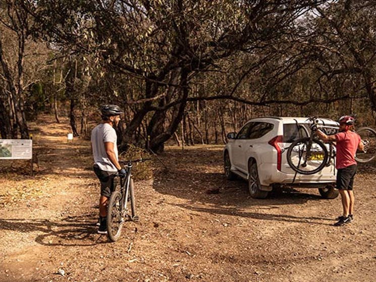 Two men take bikes off the back of a car at the start of a multi-use track in Livingstone National