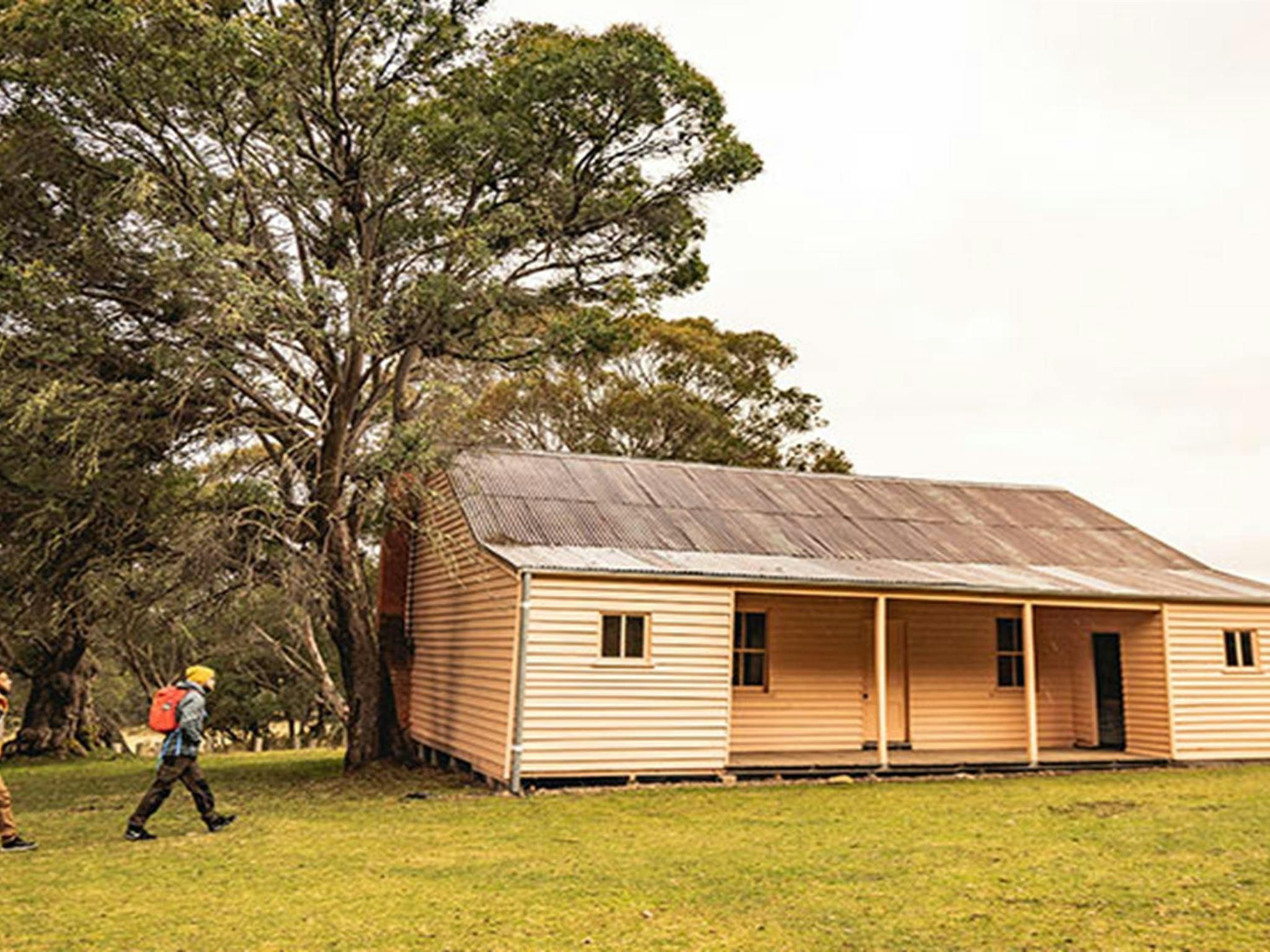 Two men walk towards Long Plain Hut in the High Plains area of Kosciuszko National Park. Photo: