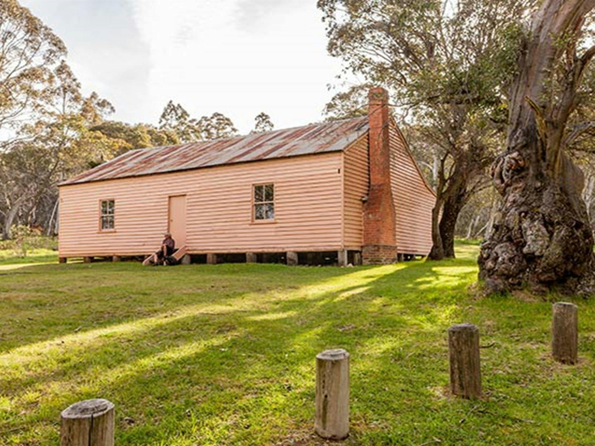 A man sits on steps outside Long Plain Hut, High Plains area, Kosciuszko National Park. Photo: