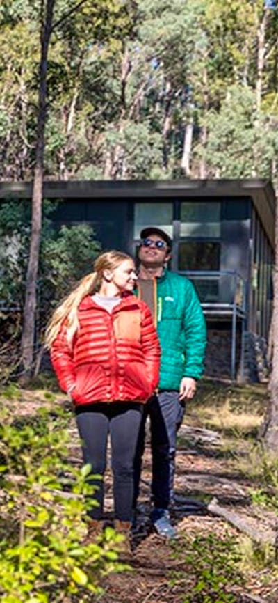 A couple walk through forest near Lyrebird Cottage, Kosciuszko National Park. Photo: Boen