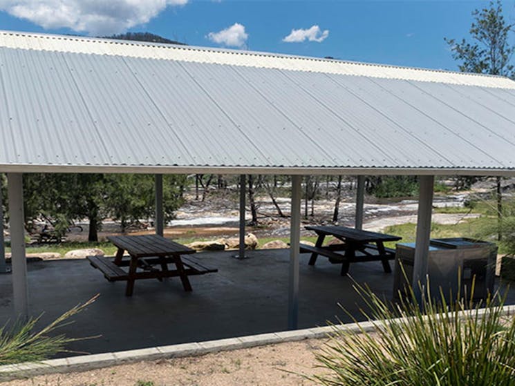 A shelter with picnic tables and a barbecue at Mann River campground and picnic area in Mann River