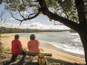 2 people sitting on a bench seat looking out the Bithry Inlet, mouth of the Wapengo Lake in Mimosa