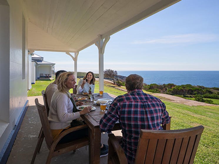 2 men and 2 women lunch at a table on the verandah outside Montague Island Head Lighthouse Keepers