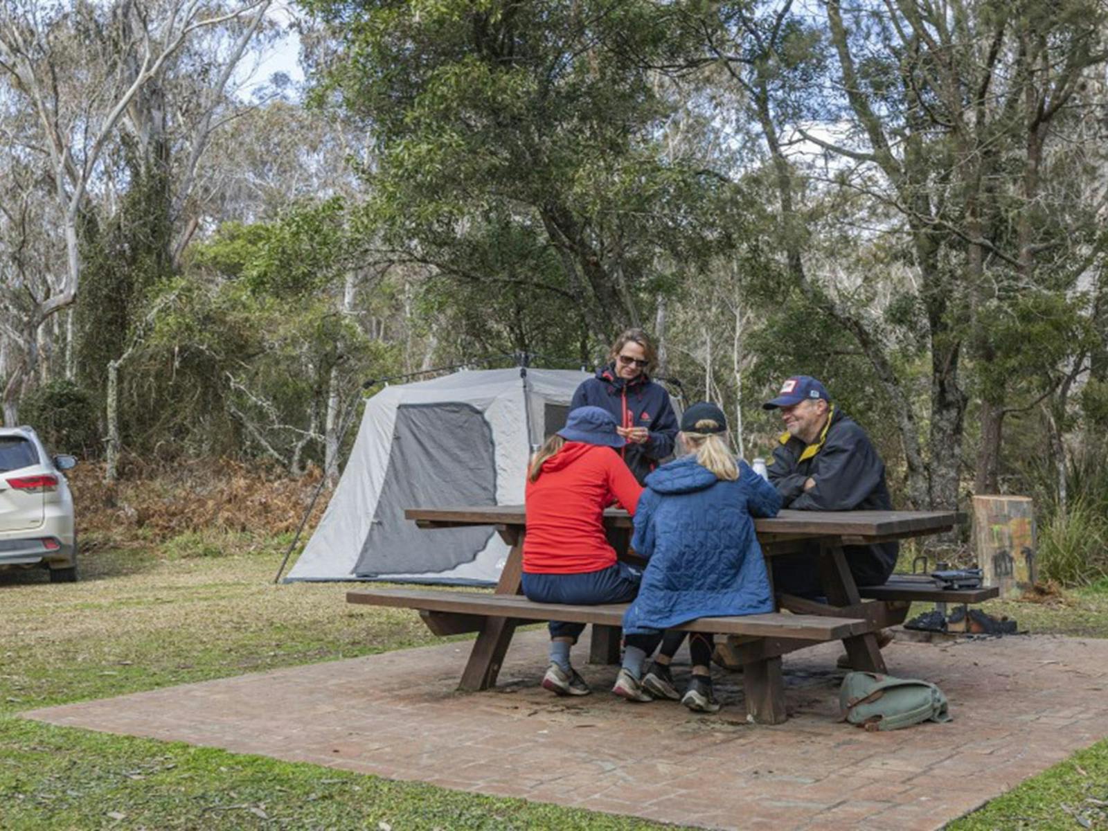 A group of friends at a picnic table next to their tent at Mooraback campground in Werrikimbe