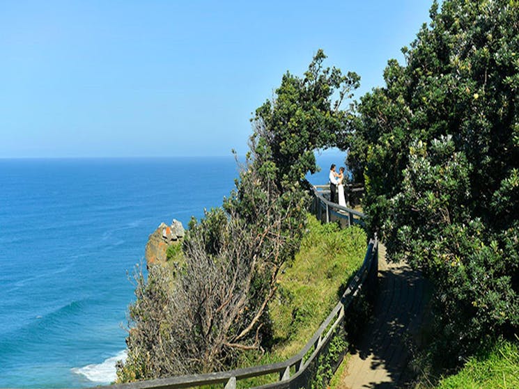 A couple standing under a natural arch created by trees at Most Easterly Point in Cape Byron State