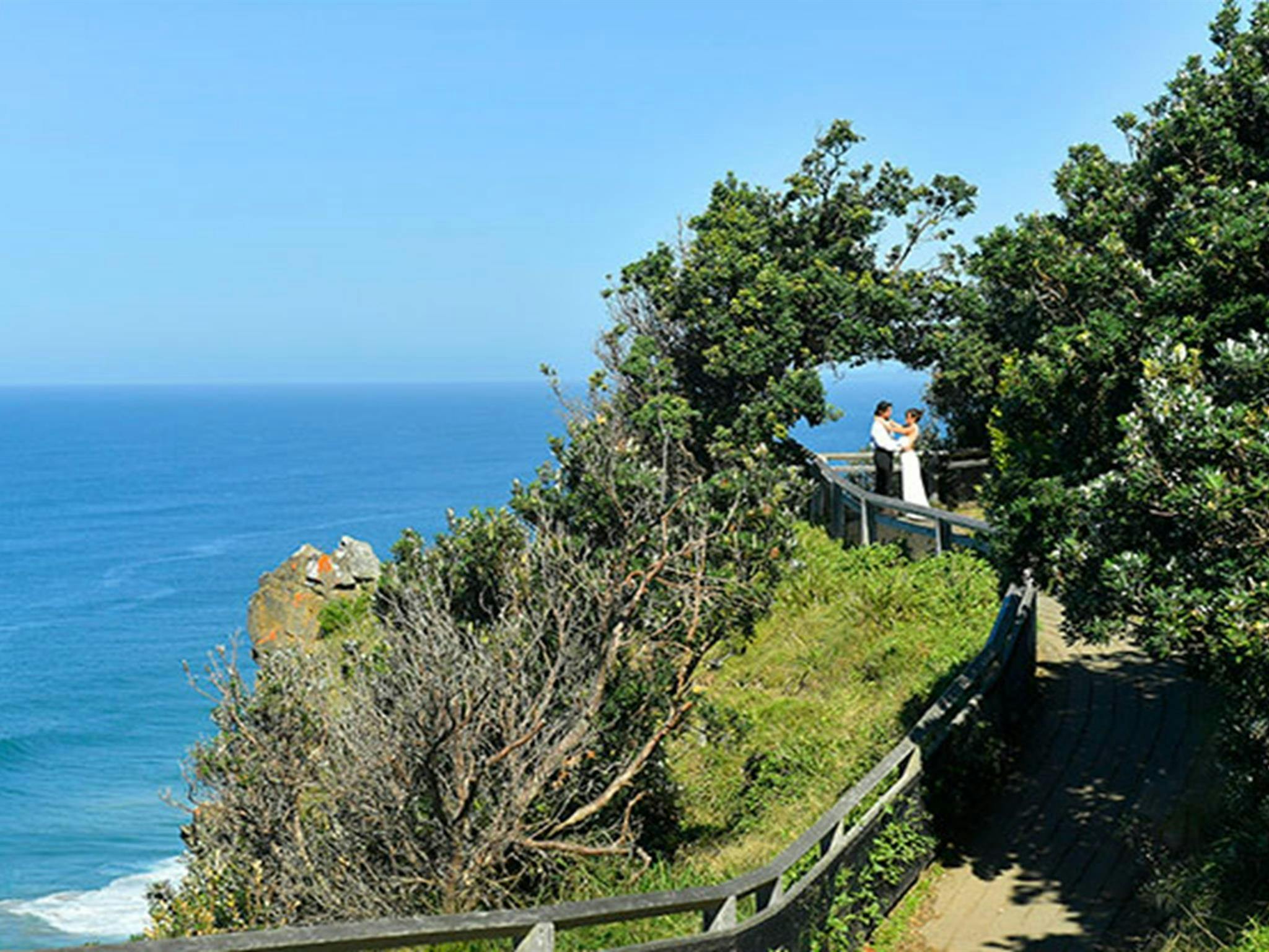 一对情侣站在纽约州拜伦角最东端由树木形成的天然拱门下。