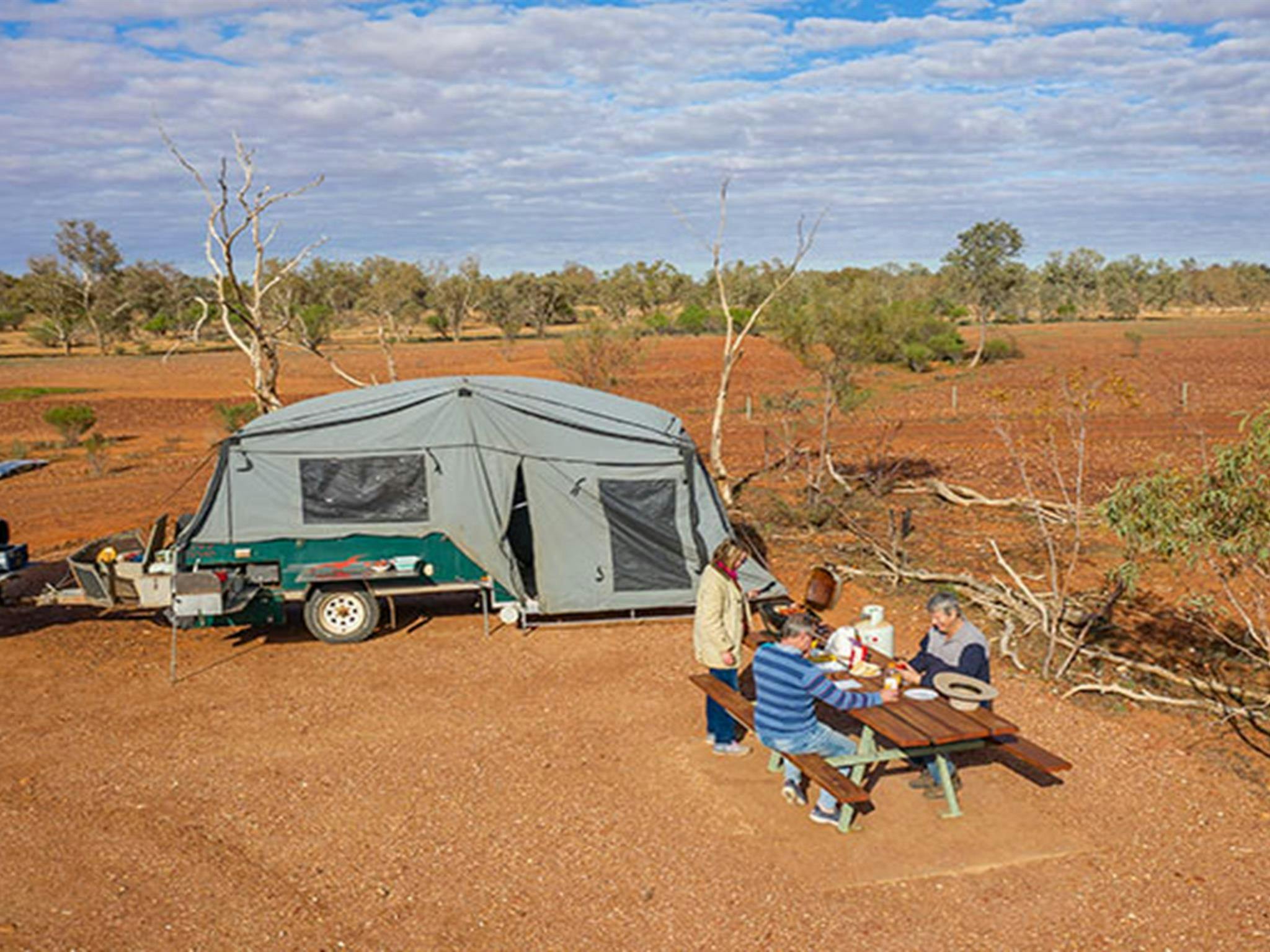 Camper frühstücken neben ihren Wohnwagen auf dem Campingplatz Mount Wood. Foto: John