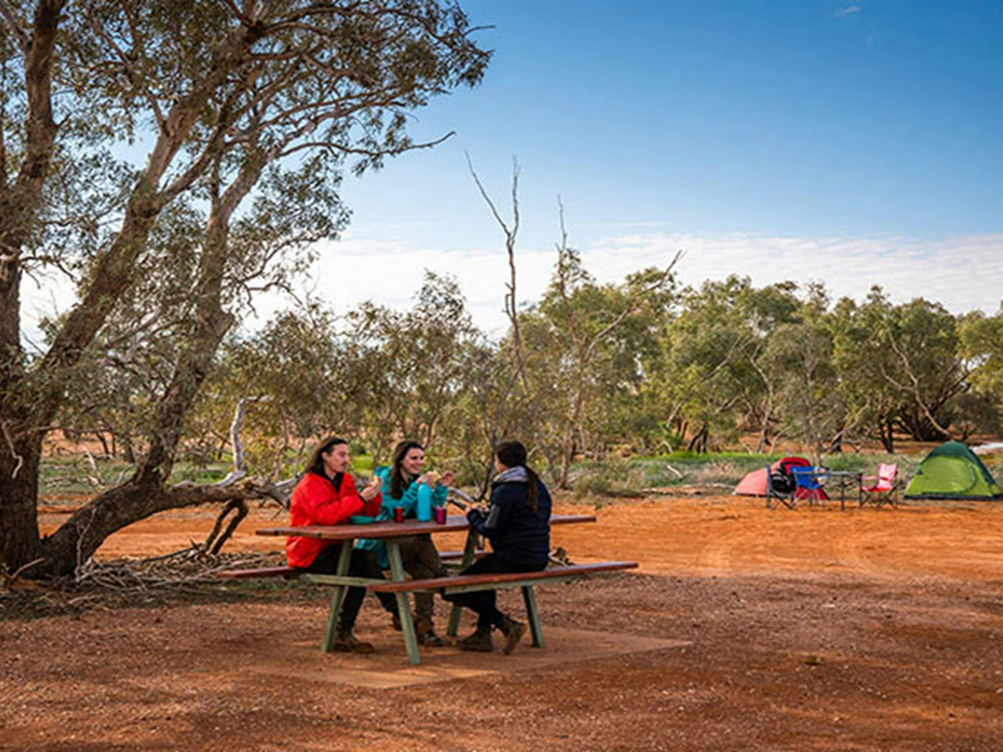 Freunde frühstücken an einem Picknicktisch auf dem Campingplatz Mount Wood. Foto: John Spencer/DPIE