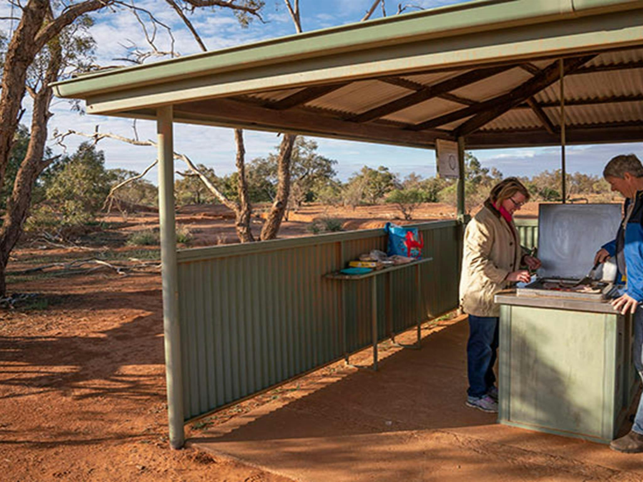 Ein Paar bereitet das Frühstück im Grillpavillon auf dem Campingplatz Mount Wood zu. Foto: John Spencer/DPIE