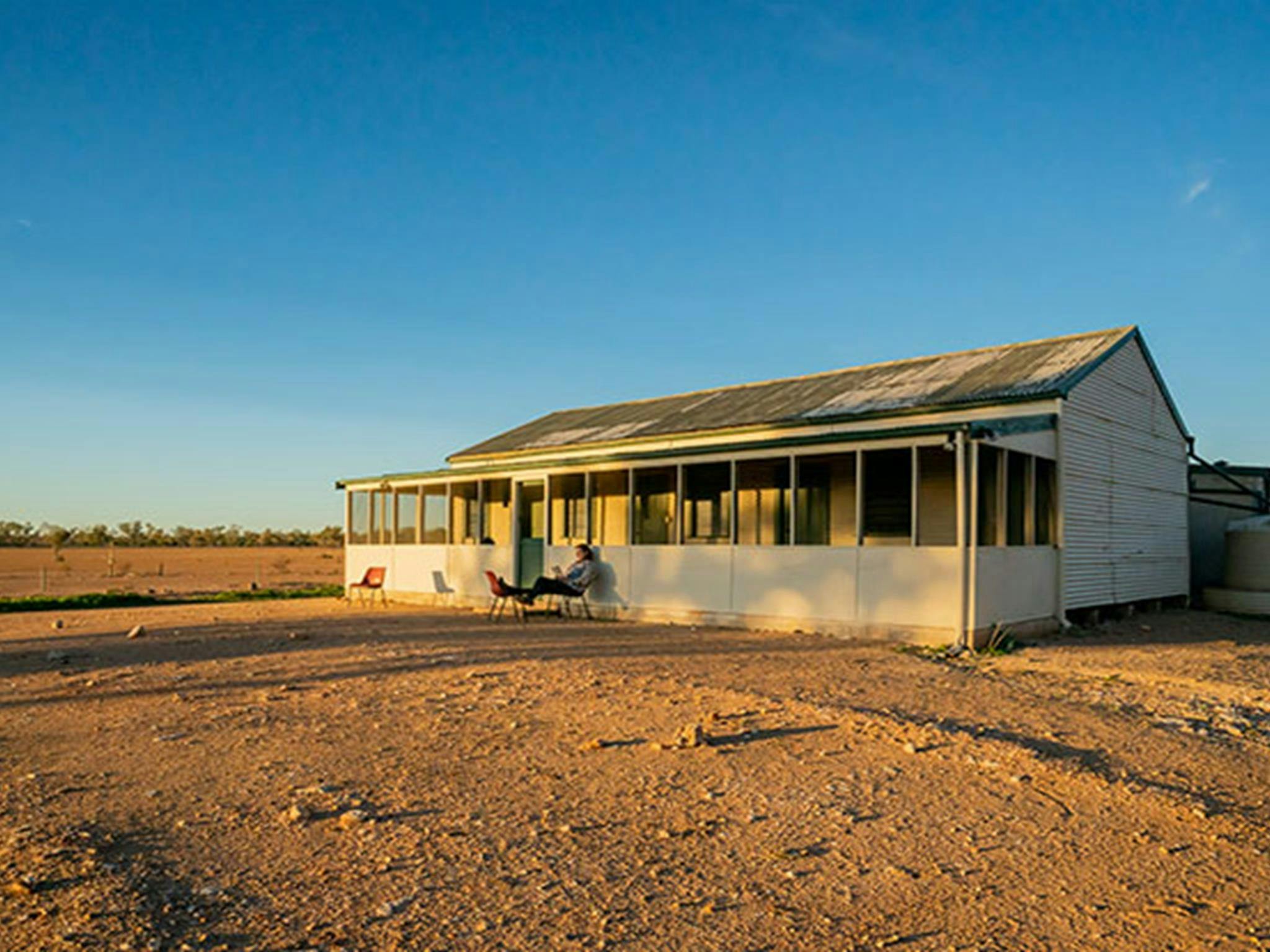 Mann liest ein Buch vor dem Schafschererwohnheim Mount Wood. Foto: John Spencer/DPIE