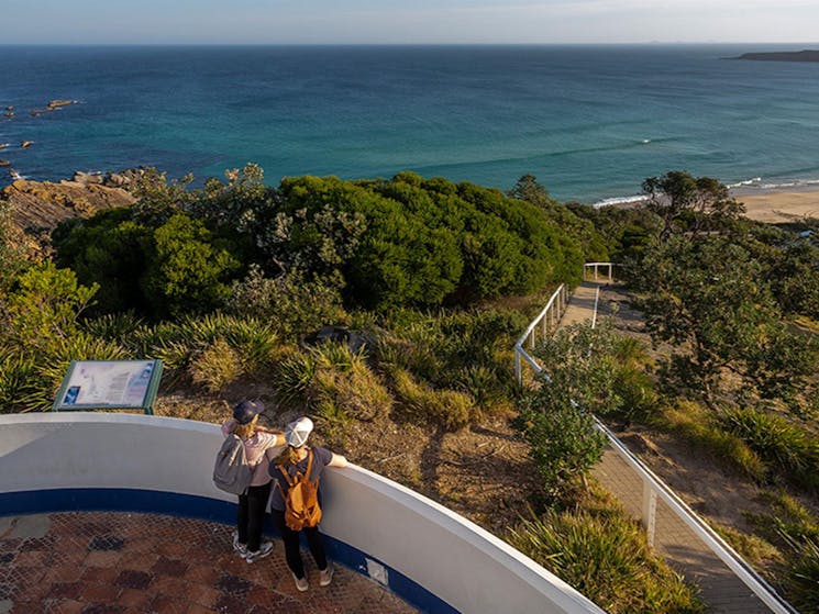An aerial photo of 2 visitors looking at the ocean views from Sugarloaf Point Lighthouse, Myall