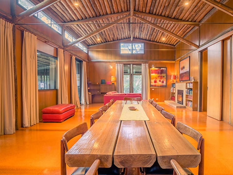Long wooden dining table and red leather couches in Myher House. Photo: OEH/John Spencer