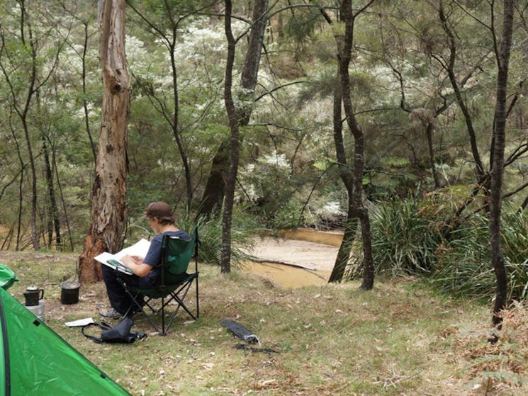 Camper relaxing by the river Newnes campground. Credit: Stephen Alton &copy; DPE