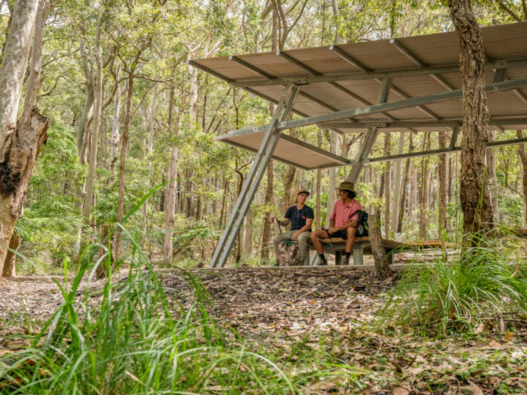 2 campers sitting under the picnic shelter at Oaky Beach campground. Credit: John Spencer &copy; DPE