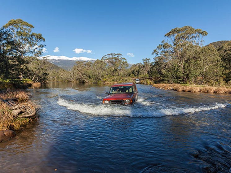 Red 4WD vehicle crosses the Swampy Plain River, Kosciuszko National Park. Photo: Murray