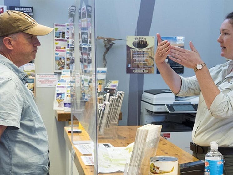 An NPWS worker gives advice to a visitor at the counter, Pilliga Forest Discovery Centre. Photo: