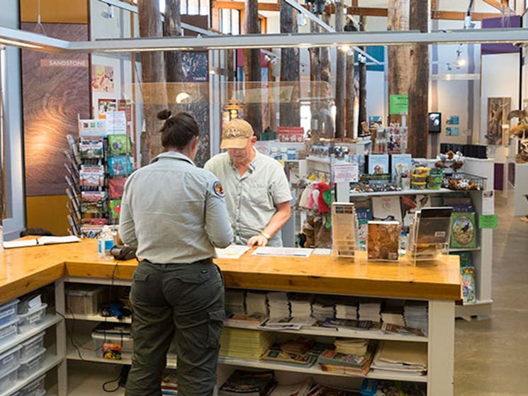 A visitor and NPWS staff member at the counter of Pilliga Forest Discovery Centre in Pilliga