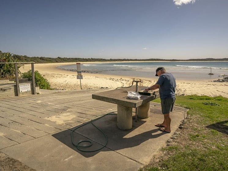 A fisherman cleaning his fish on a bench nearby the beach at Point Plomer campground, Limeburners