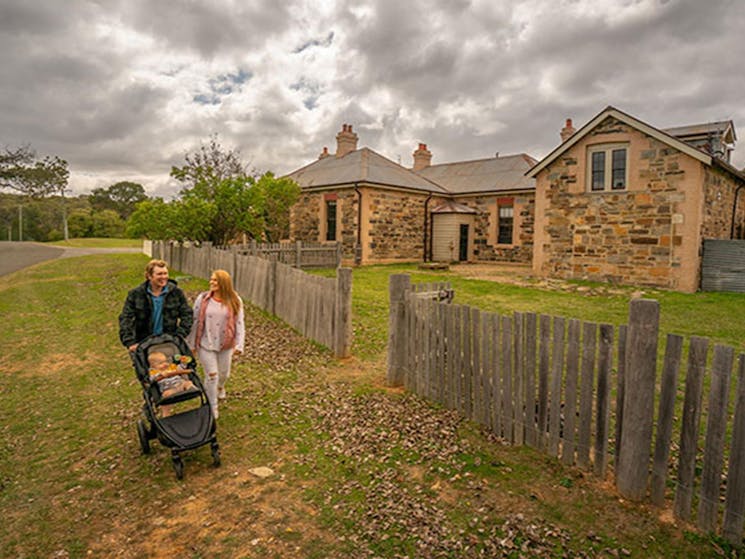 Family with baby walking past Post Office Residence and Stables in Hill End Historic Site. Photo: