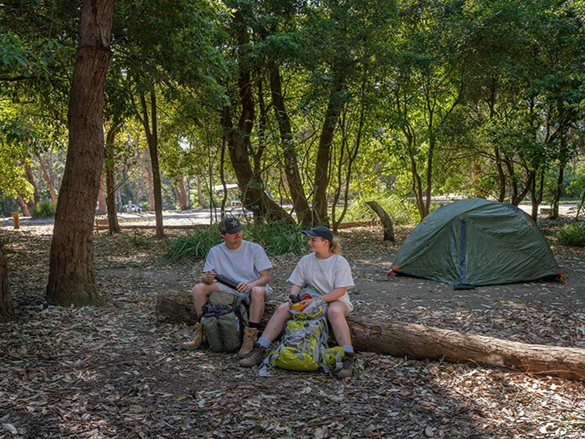 露营者在普雷蒂海滩露营地的一根圆木上休息。图片来源：John Spencer © DCCEEW