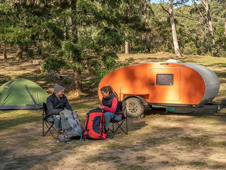 A couple preparing for a hike in front of their mini camper trailer at Private Town campground,