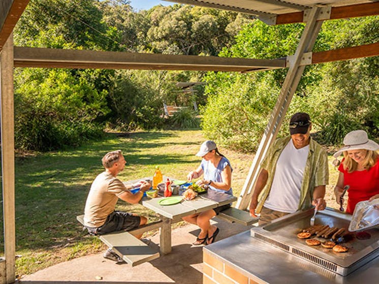 Campers cooking on the sheltered barbecue at Putty Beach campground. Photo: John Spencer/DPIE