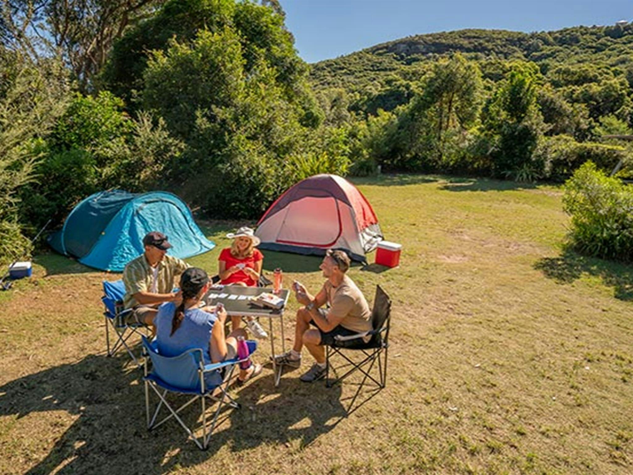 Camper sitzen und spielen Karten auf dem Campingplatz Putty Beach. Foto: John Spencer/DPIE