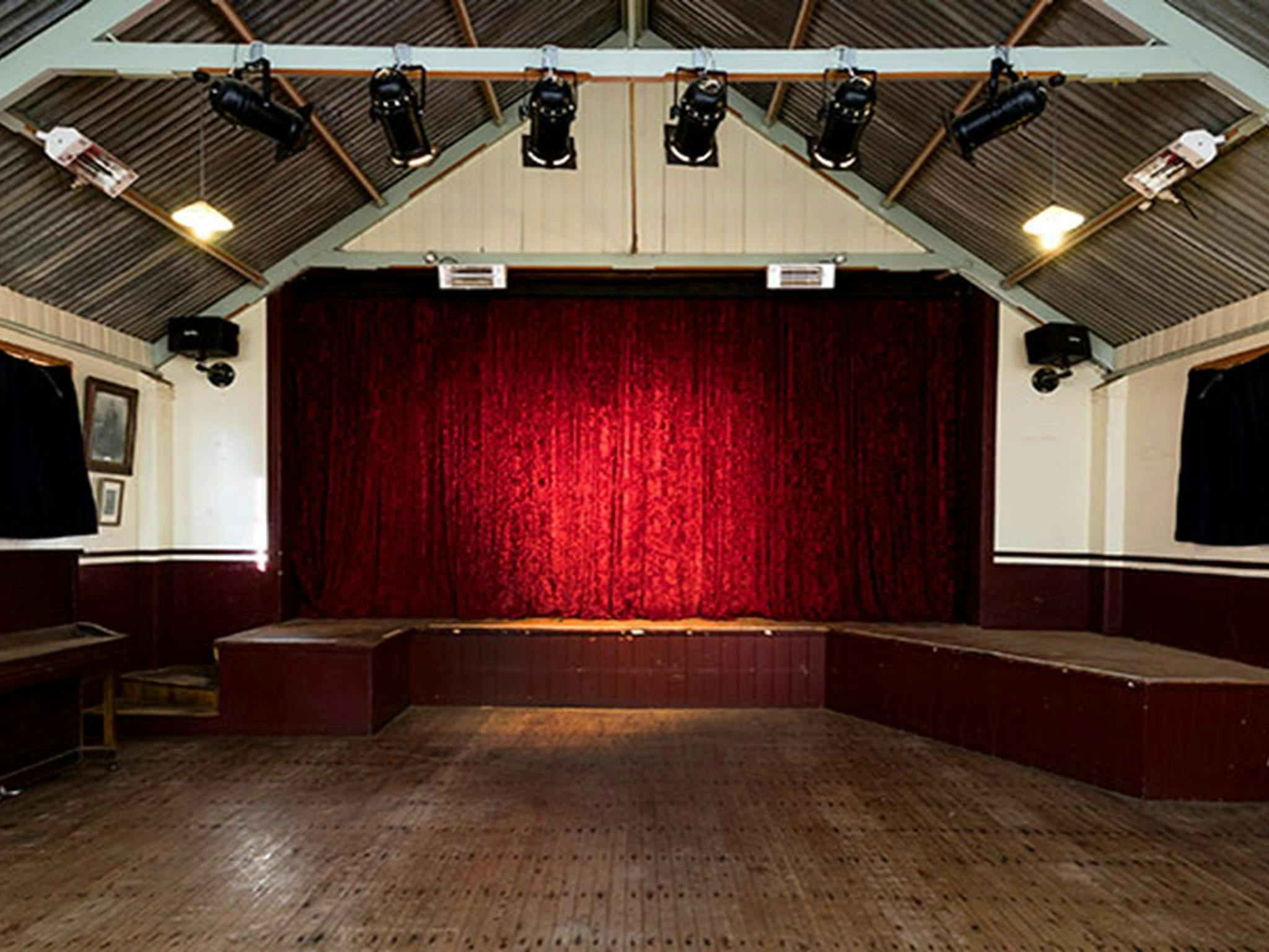 Das Innere der Royal Hall mit der Bühne im Hintergrund, hinter einem roten Vorhang im historischen Viertel Hill End.