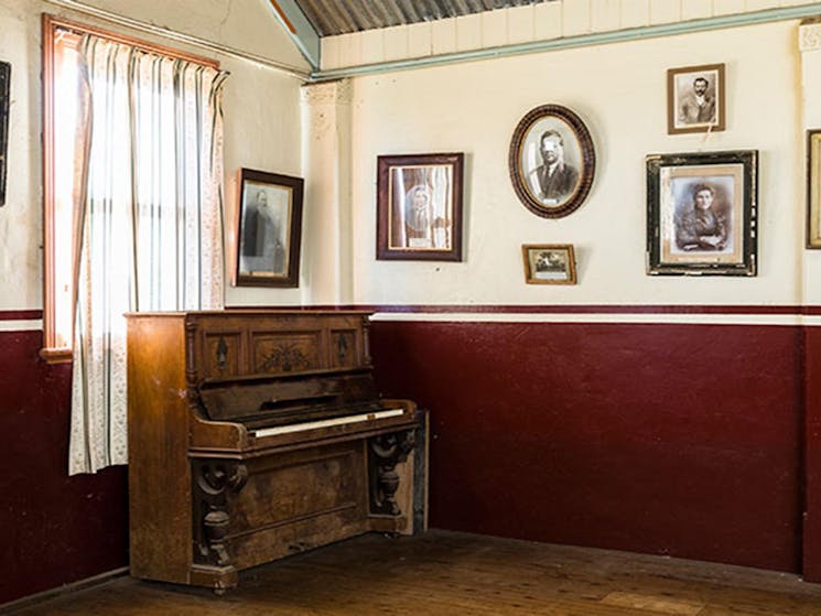 Historic photographs on the walls behind a piano in Royal Hall, Hill End Historic SIte. Photo: