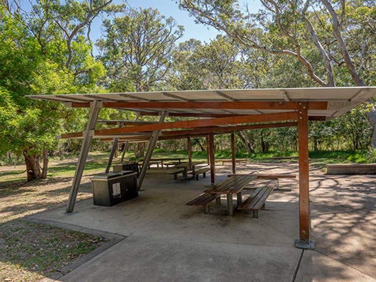A covered shelter with picnic tables in the grassy picnic area behind Seven Mile Beach. Photo: John