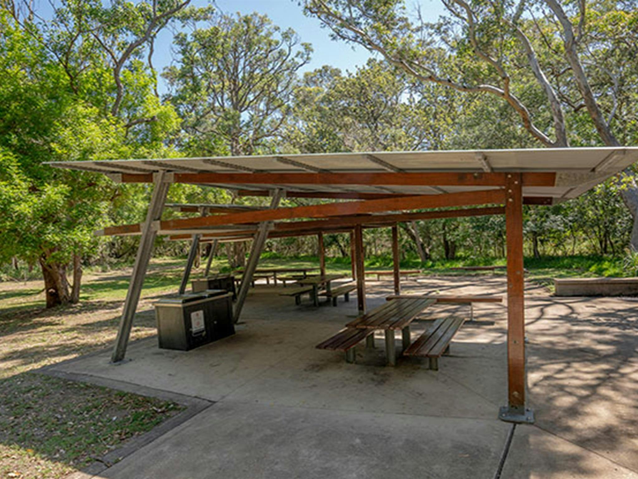 A covered shelter with picnic tables in the grassy picnic area behind Seven Mile Beach. Photo: John
