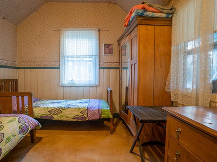 A bedroom with two single beds, a wardrobe and chest of drawers at Slippery Norris Cottage in