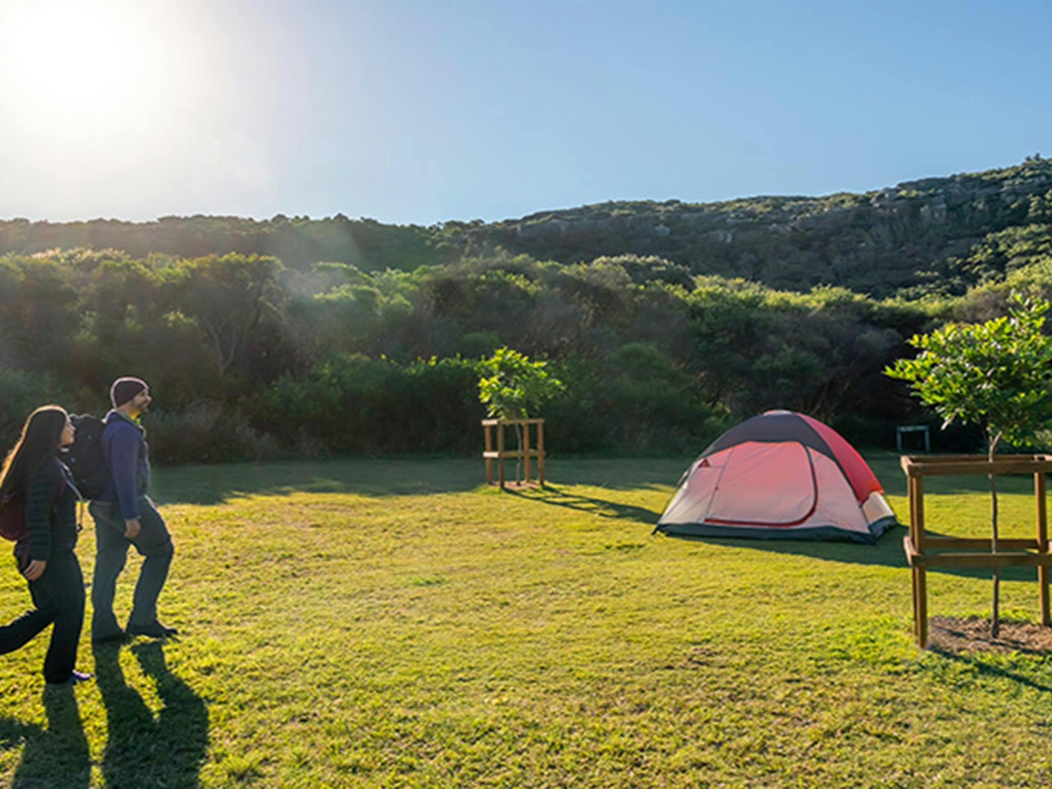 Zwei Wanderer auf dem Weg zu ihrem Zelt auf dem Campingplatz Tallow Beach im Bouddi-Nationalpark. Foto: John