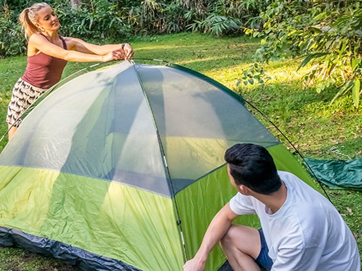 2 campers setting up a tent on the grass. Photo: John Spencer/DPIE