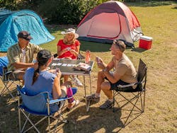 A group of friends playing cards next to their tents. Photo: John Spencer/DPIE