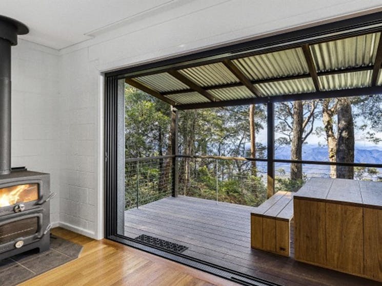 The indoor fireplace and view of the deck at The Chalet in New England National Park. Photo: