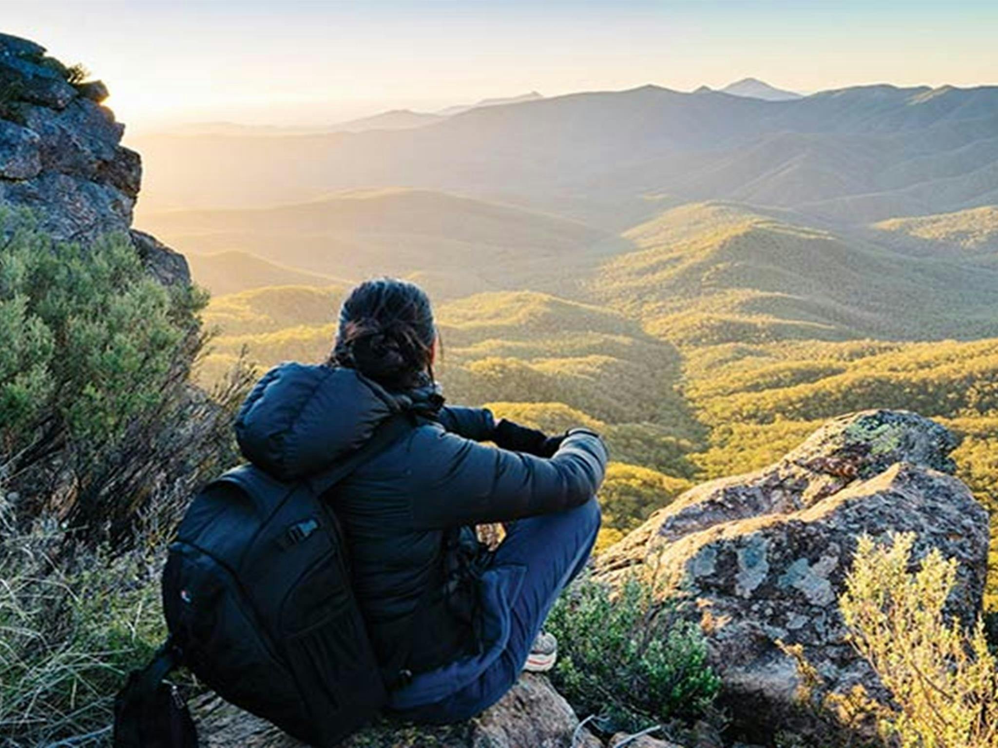 Eine Frau hockt auf einem Felsen und genießt den Sonnenuntergang vom Aussichtspunkt „The Governor Lookout“ aus. Foto: Simone