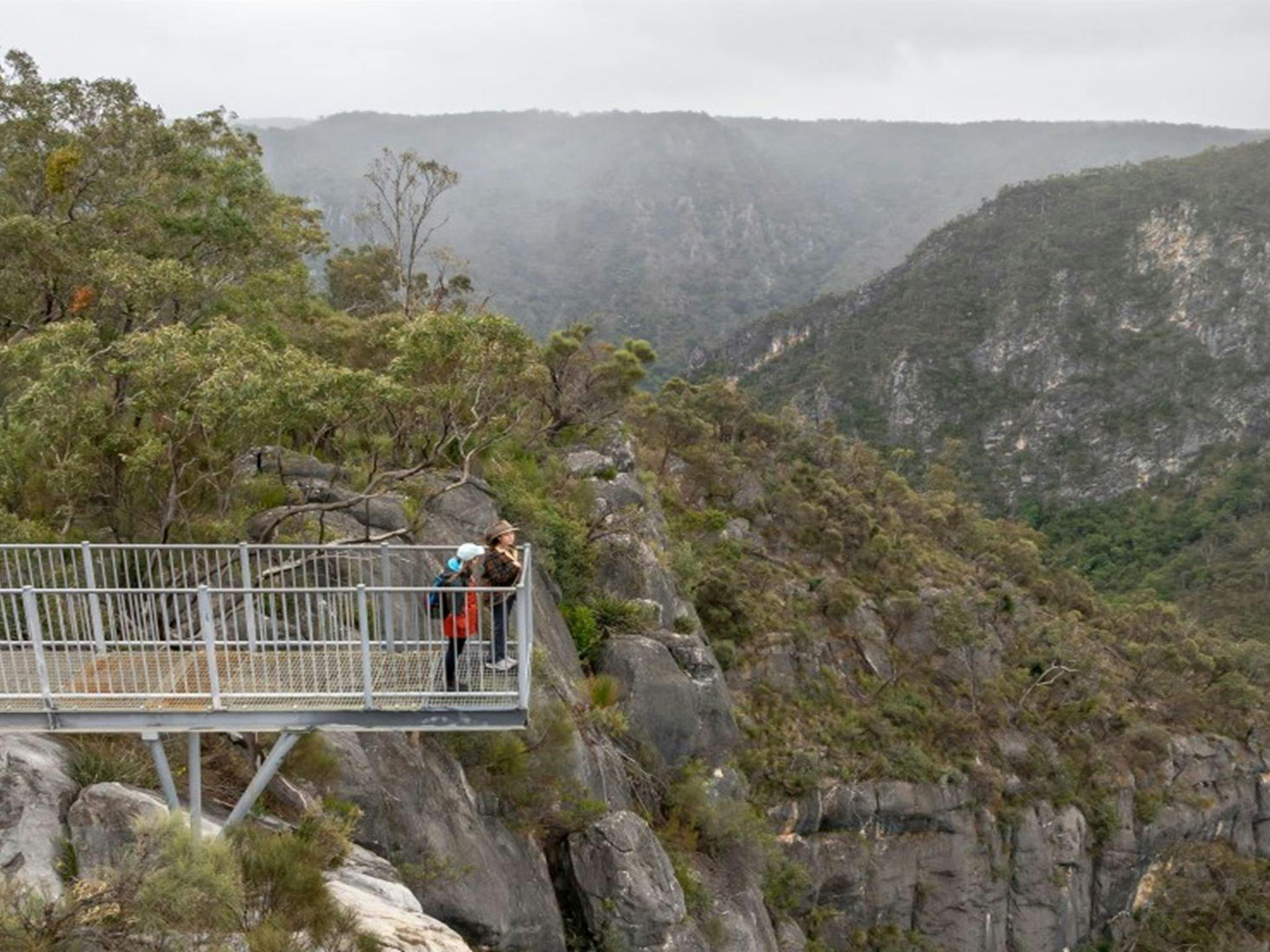 Two people enjoying the view at The Lookdown lookout surrounded by mountains in Bungonia National