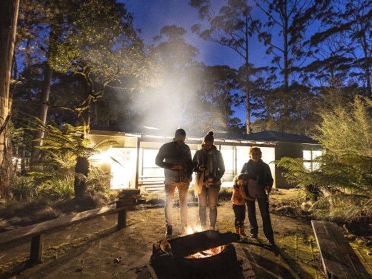 A family gathered around the firepit at night at The Residence, New England National Park. Photo: