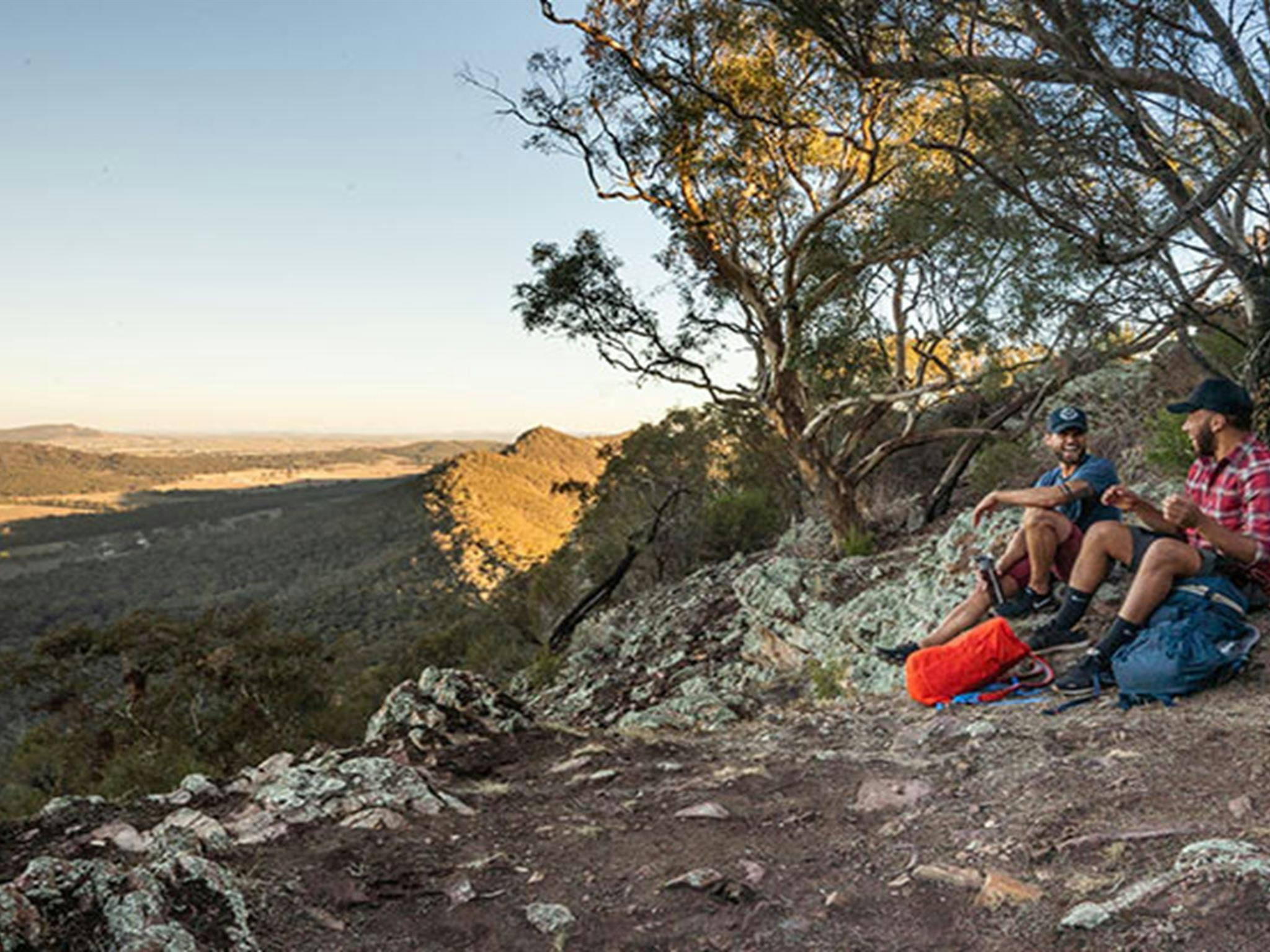 Two men sit on the ground at a viewpoint in The Rock Nature Reserve - Kengal Aboriginal Place.