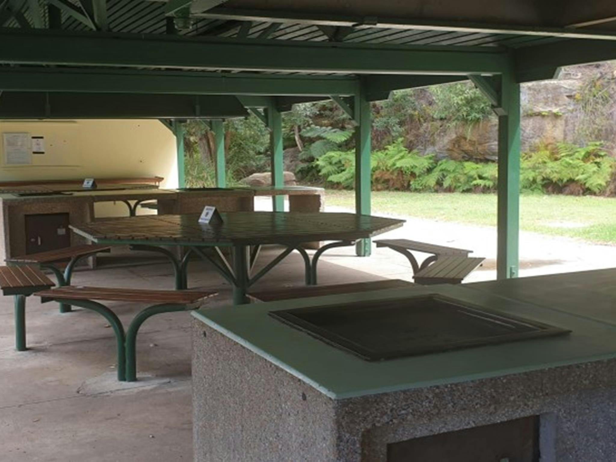 Picnic tables and a barbecue at The Station picnic shelter in Ku-ring-gai Chase National Park.