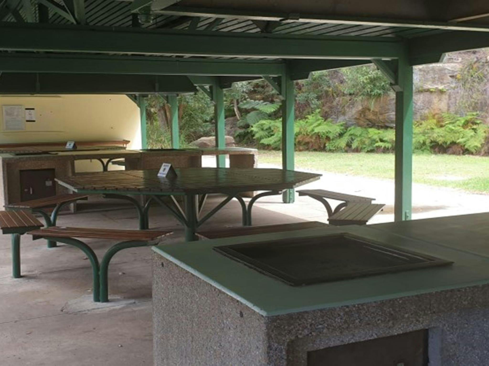 Picnic tables and a barbecue at The Station picnic shelter in Ku-ring-gai Chase National Park.