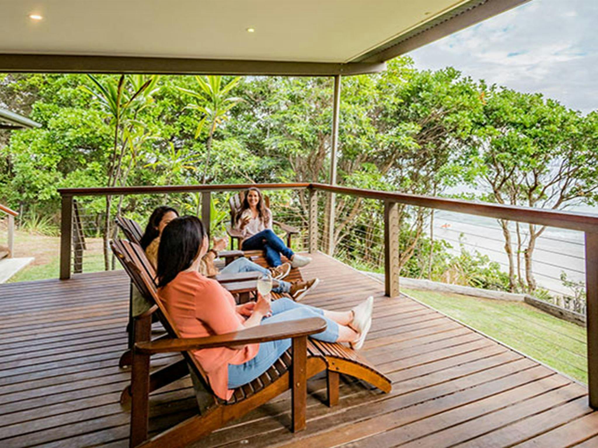 3 friends having a drink on the balcony at Thomson Cottage. Photo: Sera Wright/DPIE