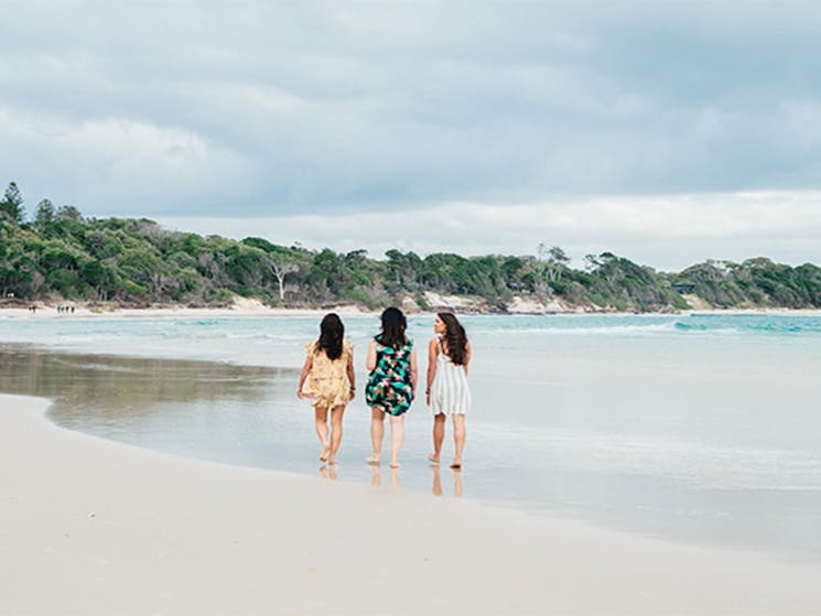 3 friends walking on The Pass beach in Cape Byron State Conservation Area. Photo: Sera Wright/DPIE