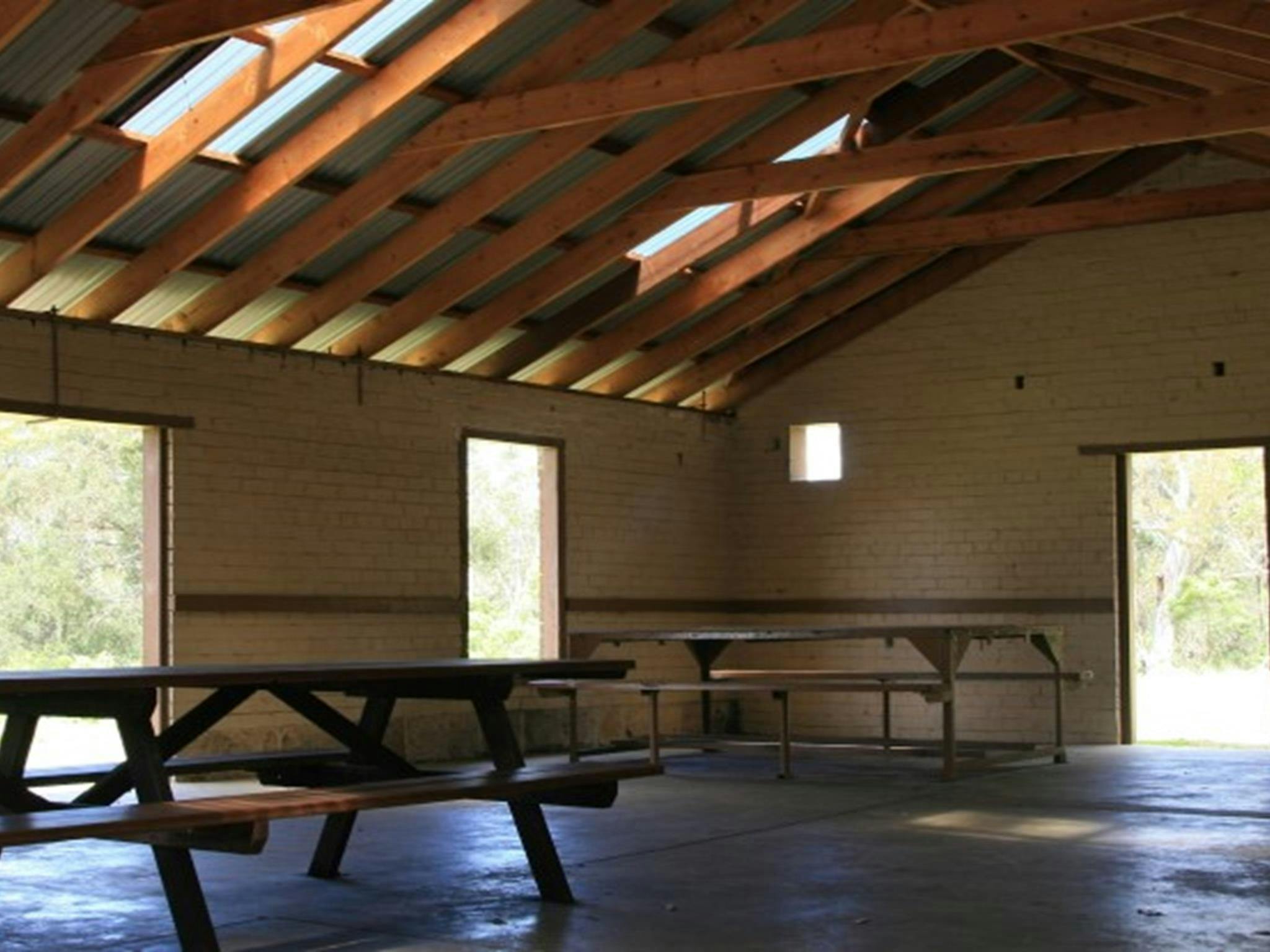 Picnic tables inside a large picnic shelter at Tunks Hill picnic area in Lane Cove National Park.